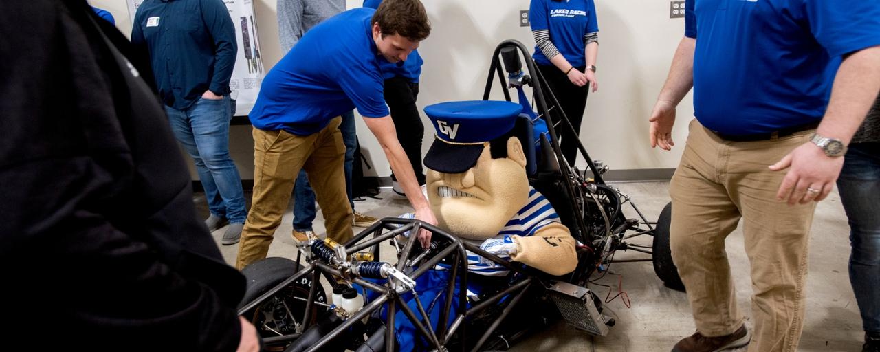 A race car with men in it and standing around it